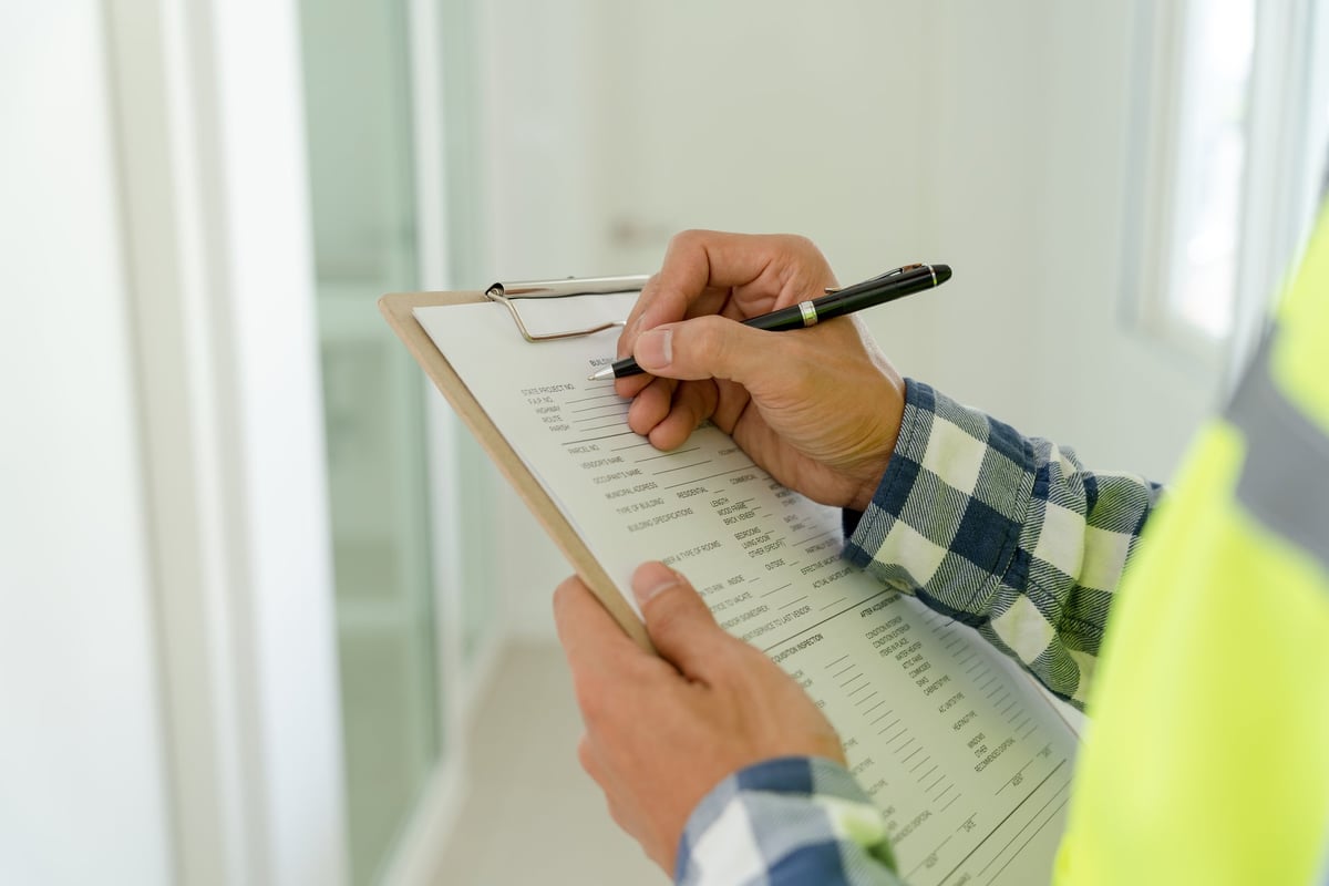 Home inspector reviewing checklist and inspection report at property